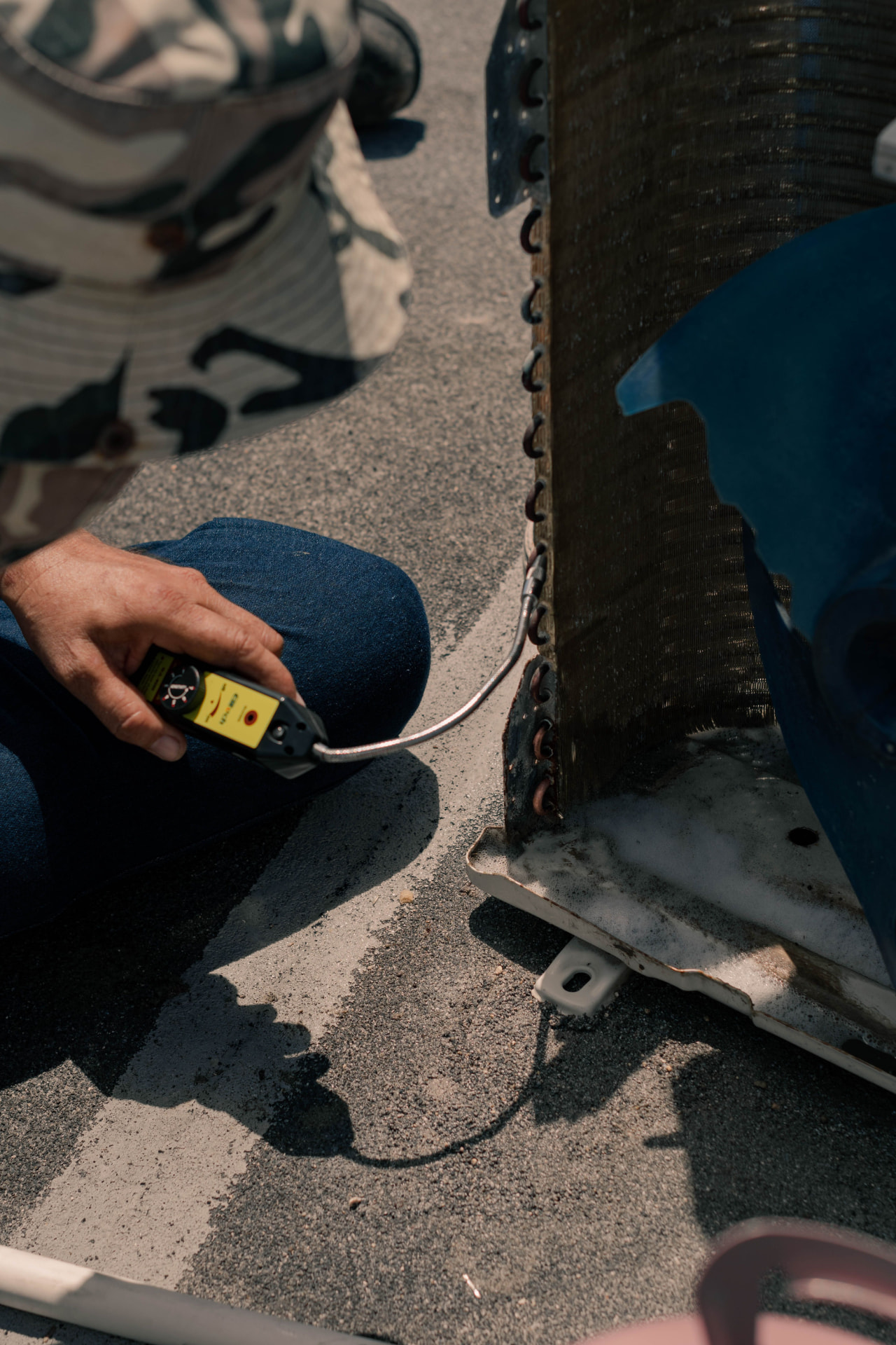 A technician testing an air conditioning unit with a handheld gauge