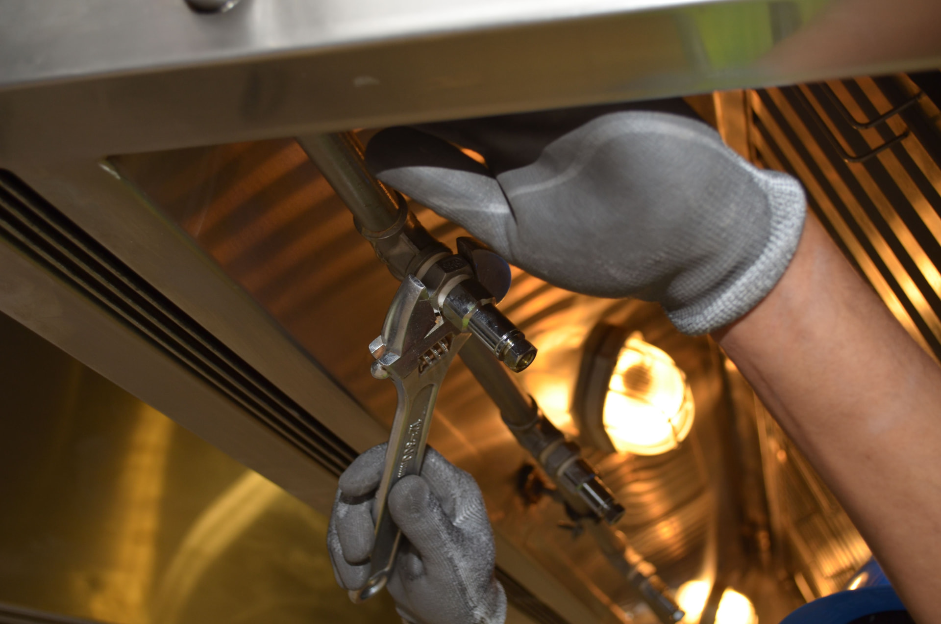A plumber tightening a valve under a sink with a wrench