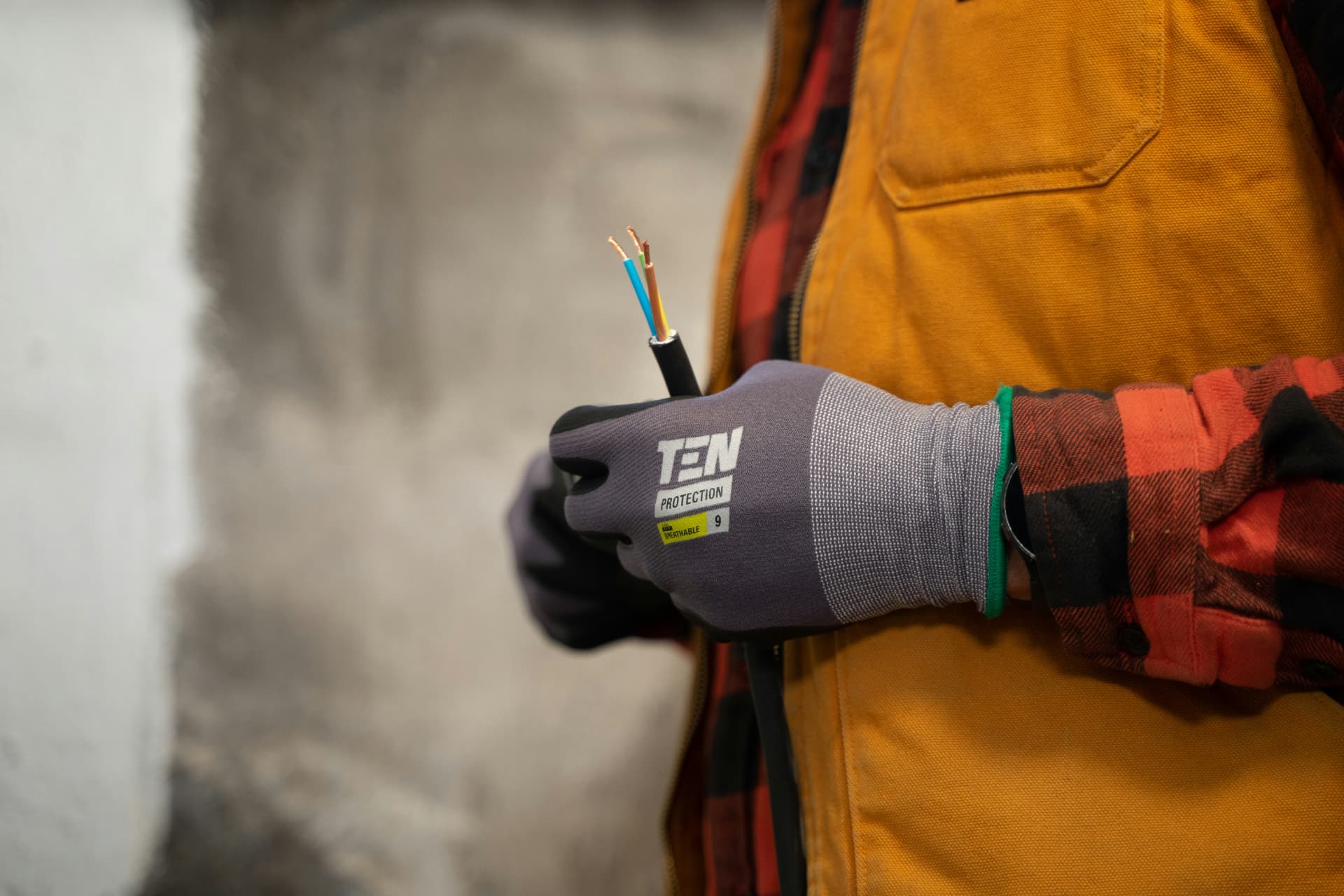 A gloved electrician holding a stripped electrical cable